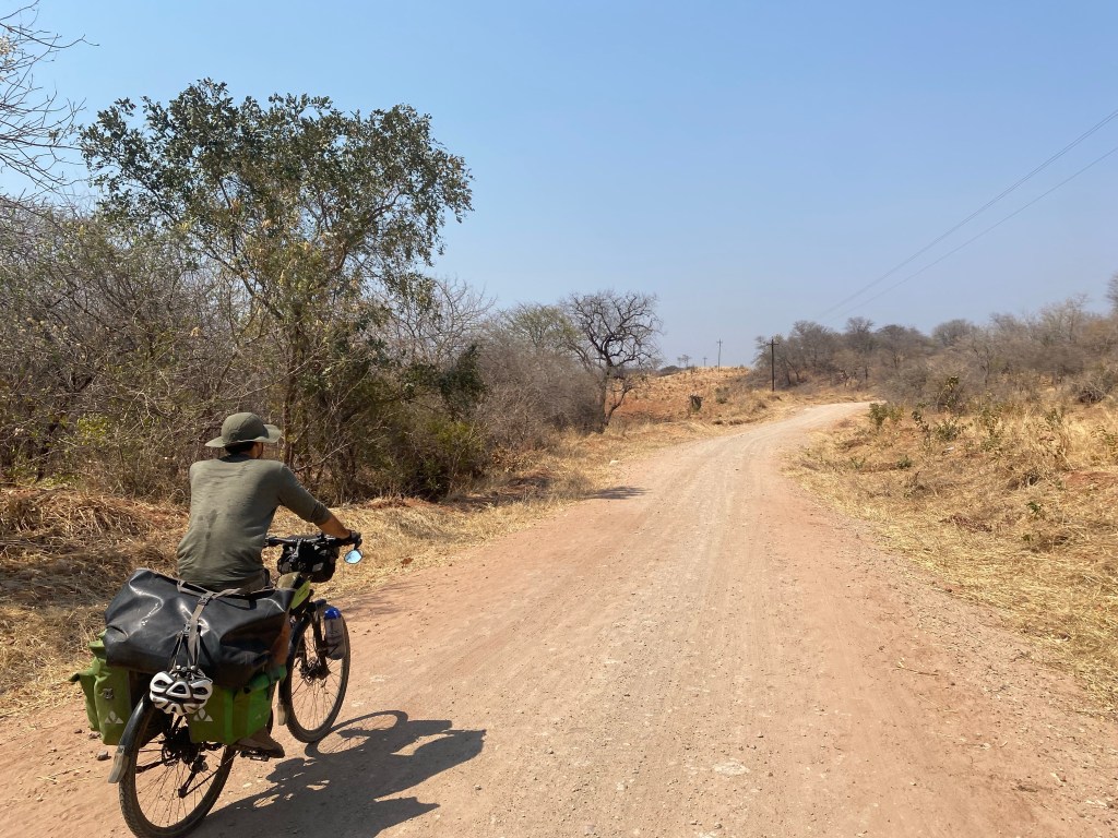 Javi biking on a dirt road in Zimbabwe next to lake kariba
