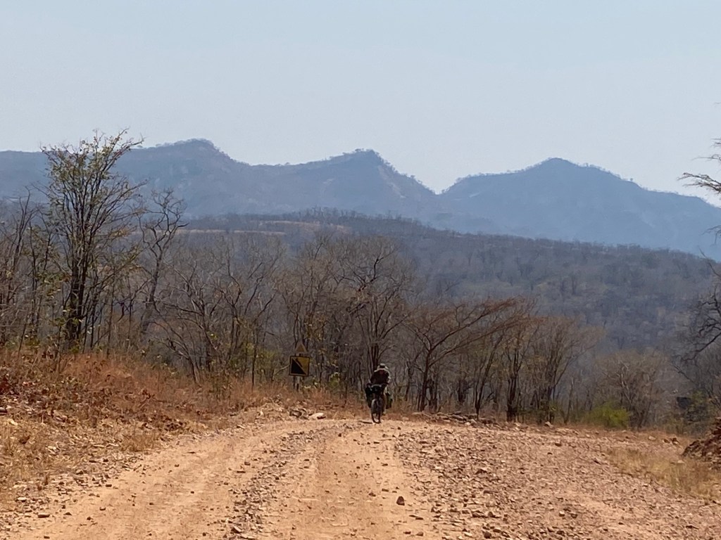 Javi riding his bicycle uphill in Zimbabwe