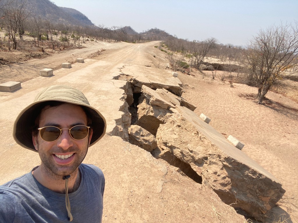 Cyclist passing a broken bridge in Zimbabwe