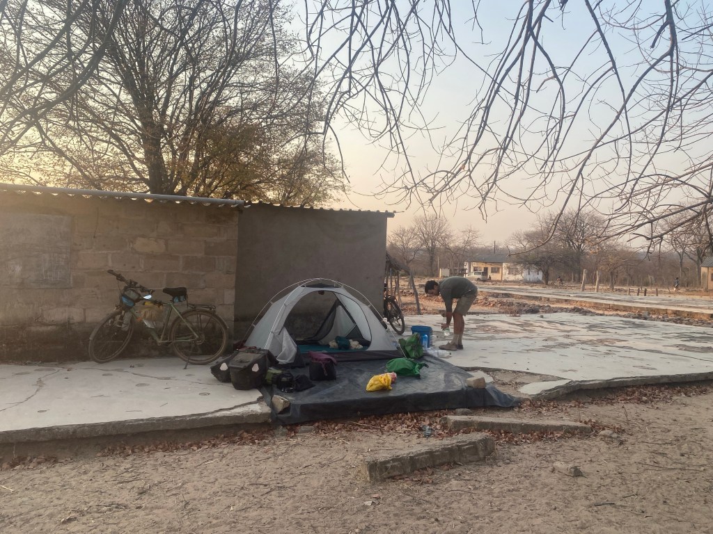 Cyclist pitching a tent in a school in Zimbabwe