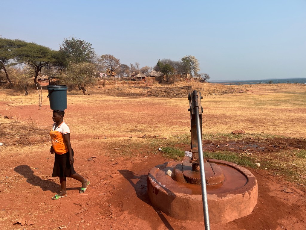 Woman carrying water from borehole in fisherman village in Zimbabwe