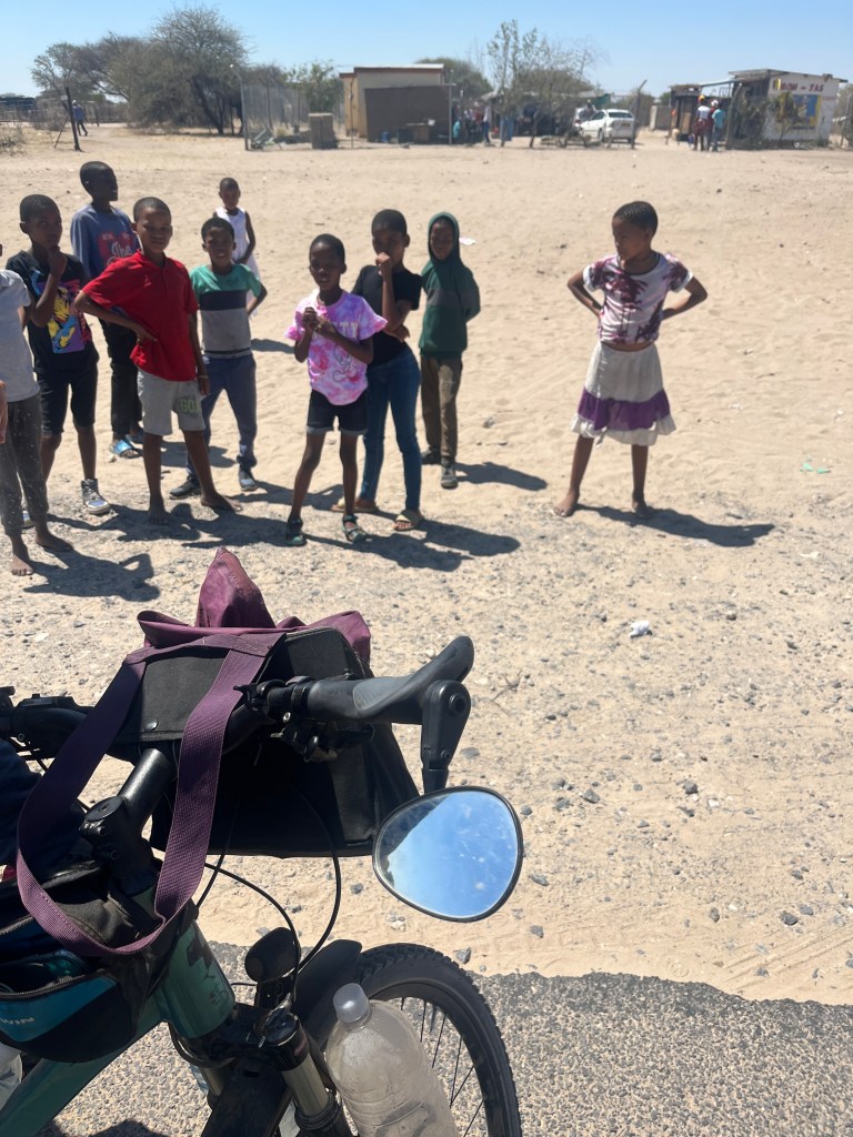 Many kids watching a cyclist in Botswana 