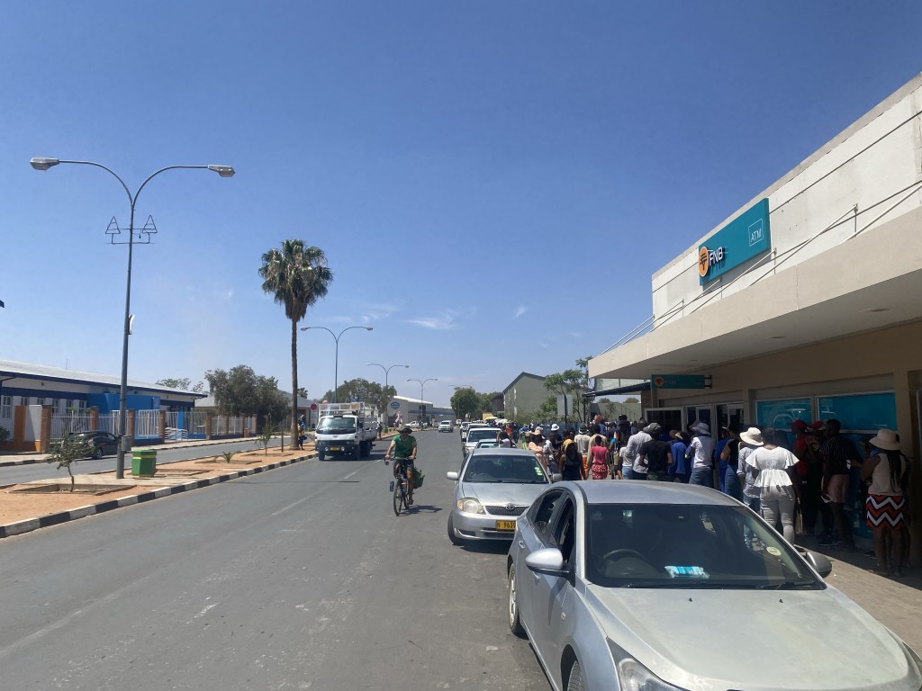 A cyclist and large queue by a bank in gobabis 
